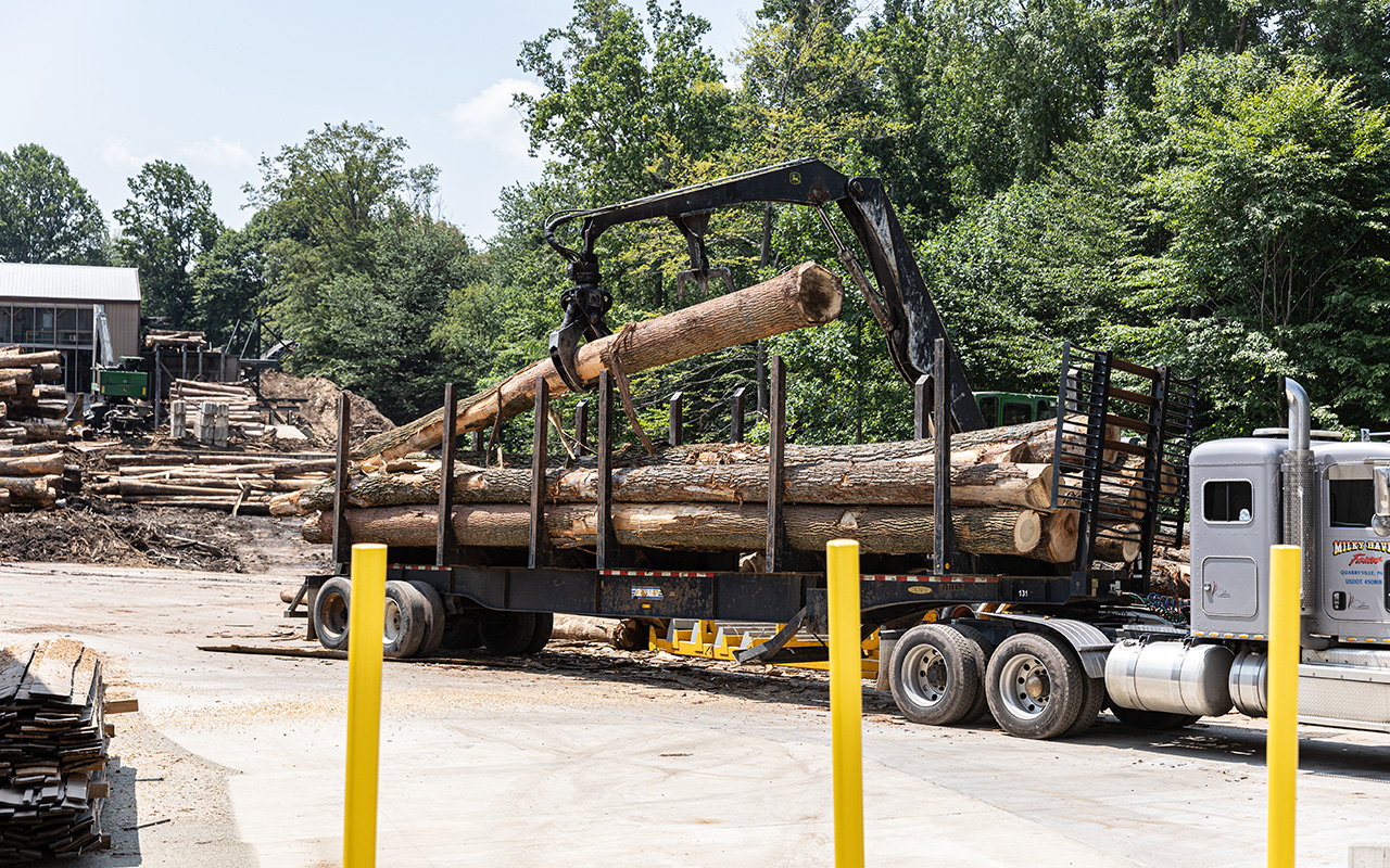 knuckleboom loader removing logs from a semi trailer